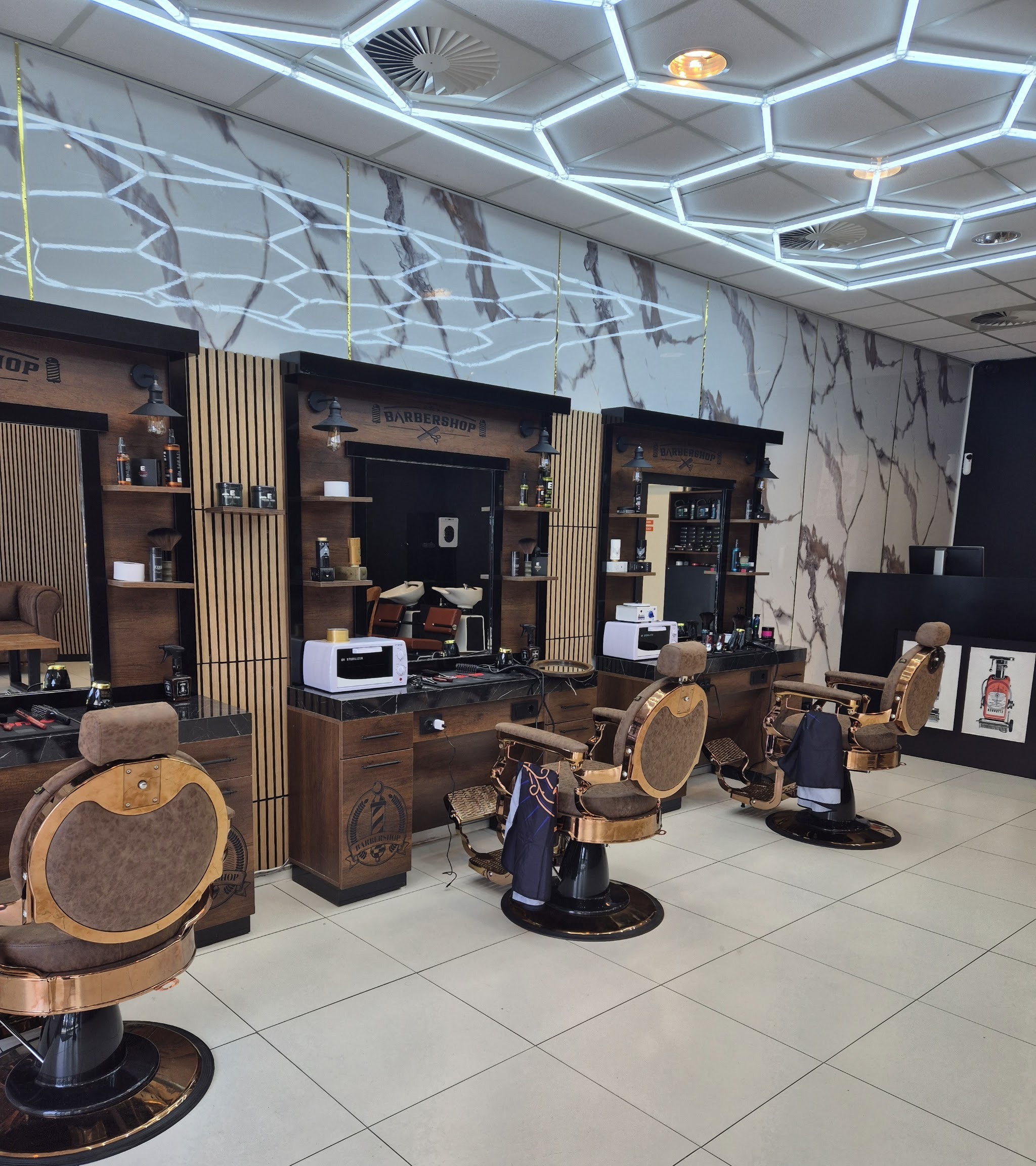 Het interieur van Mo The Barbershop: drie leren kappersstoelen, houten lamellen, marmeren wand en een plafond van zeshoekige lampen