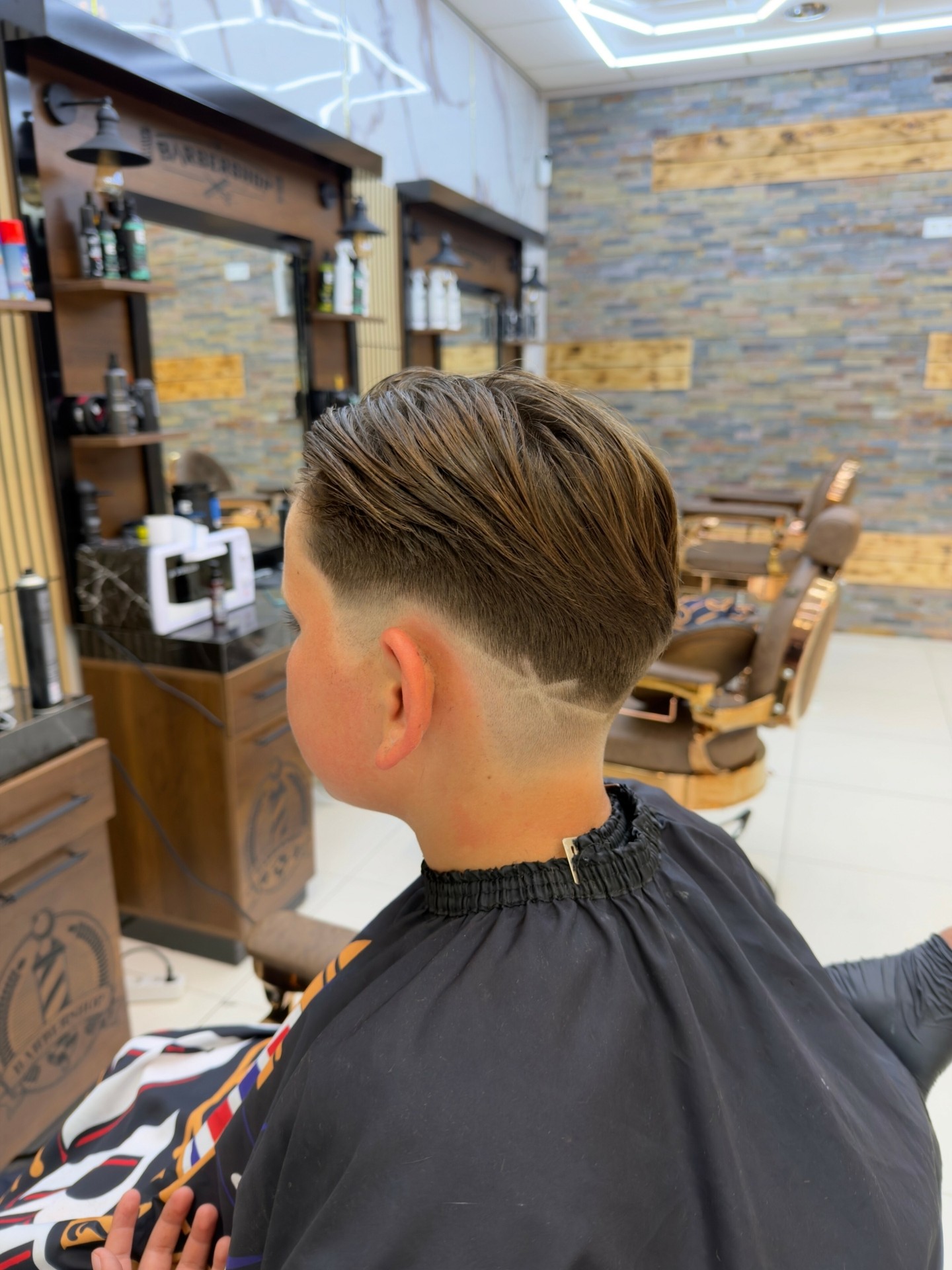 Een jongen met een vers geknipte skin fade, van achteren gezien in de barbershop